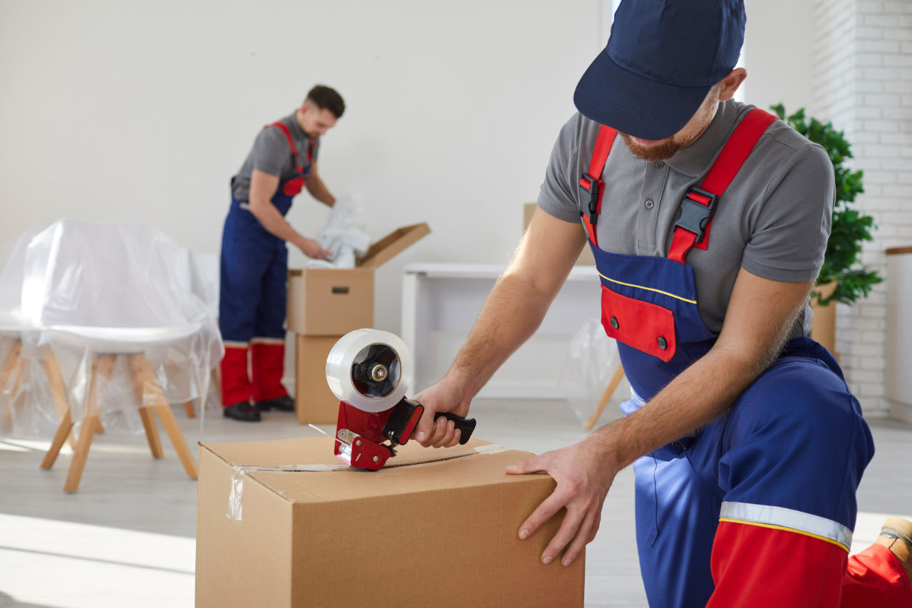 Worker from moving company or delivery service sealing cardboard box with tape dispenser