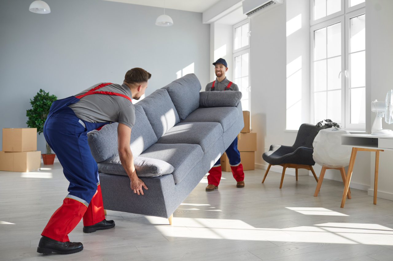 Two young men who work at moving company and delivery service lift up heavy sofa